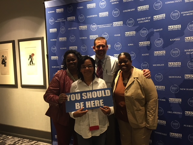 Chad Gundry with group of NASDE conference attendees with the sign "You Should Be Here"