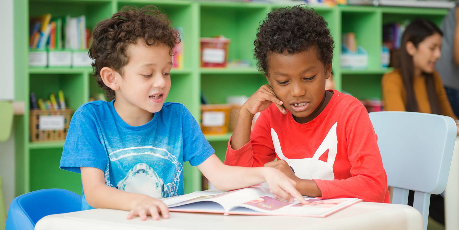 Two boys reading a book together in class